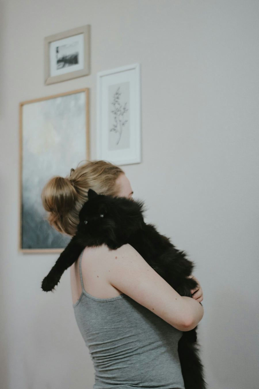 Mujer abrazando con cariño a su gato negro en casa